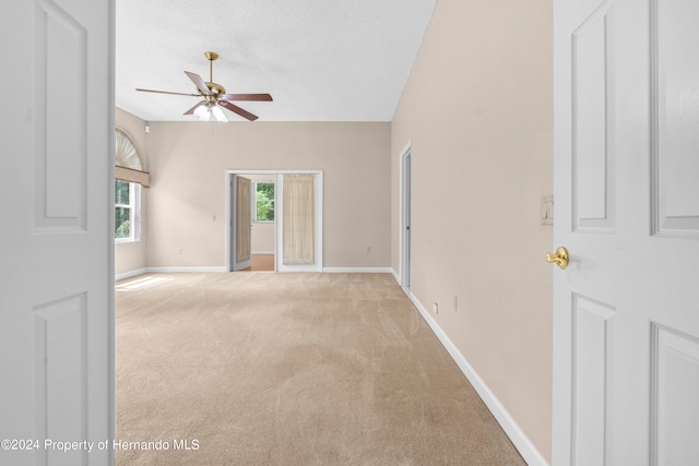 empty room with ceiling fan, a textured ceiling, and light carpet