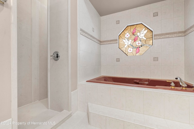 bathroom with tile walls, tile patterned flooring, and separate shower and tub