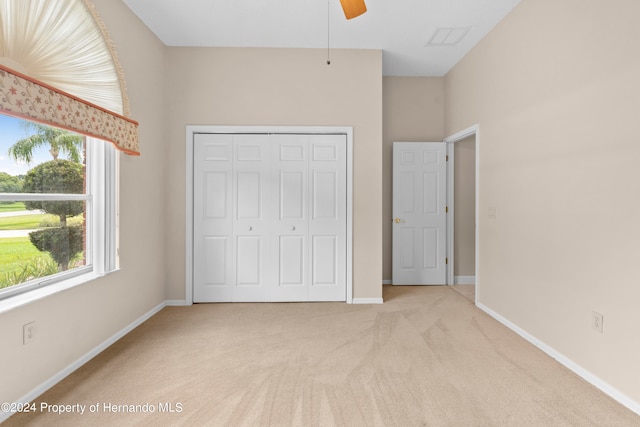 unfurnished bedroom featuring light colored carpet, ceiling fan, and a closet