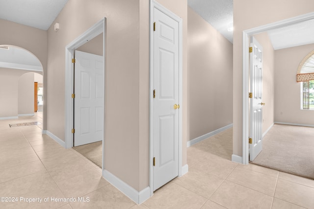 hall with a textured ceiling and light tile patterned flooring