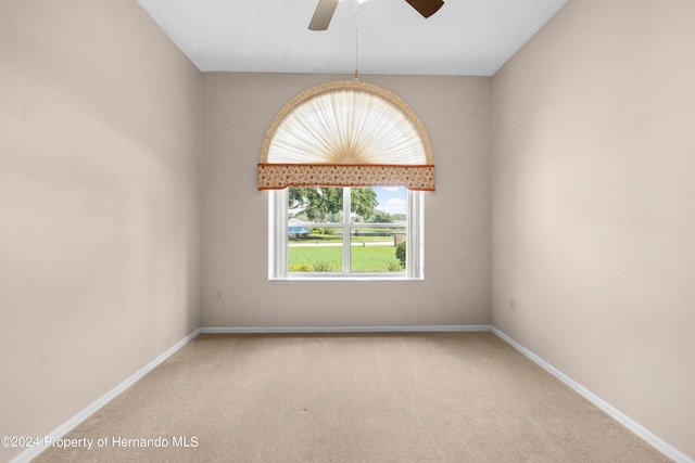 carpeted spare room featuring ceiling fan