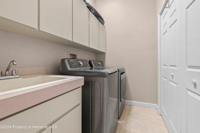 washroom featuring separate washer and dryer, cabinets, sink, and light tile patterned floors