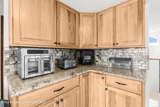 kitchen featuring light brown cabinetry, tasteful backsplash, and light stone countertops