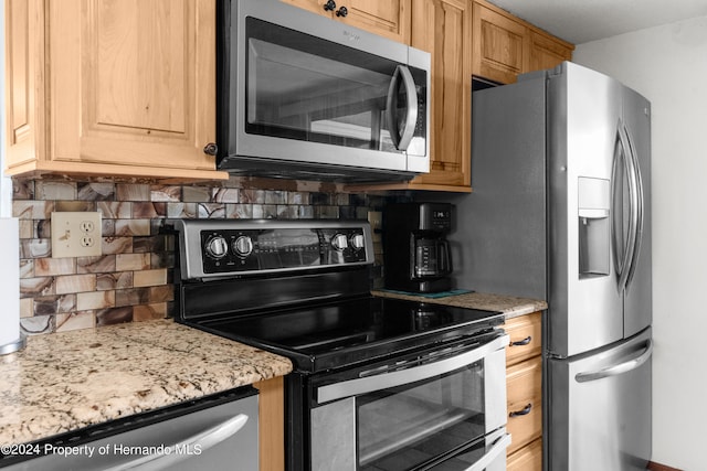 kitchen featuring appliances with stainless steel finishes, light stone counters, and backsplash