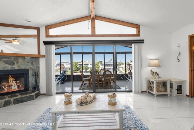 tiled living room featuring a fireplace, ceiling fan, a textured ceiling, and lofted ceiling with beams