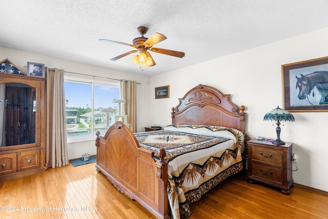 bedroom featuring ceiling fan, a textured ceiling, and light hardwood / wood-style flooring