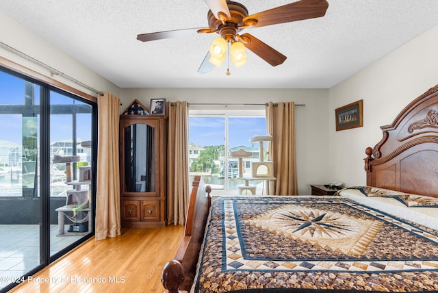 bedroom featuring access to exterior, light hardwood / wood-style floors, a textured ceiling, and ceiling fan