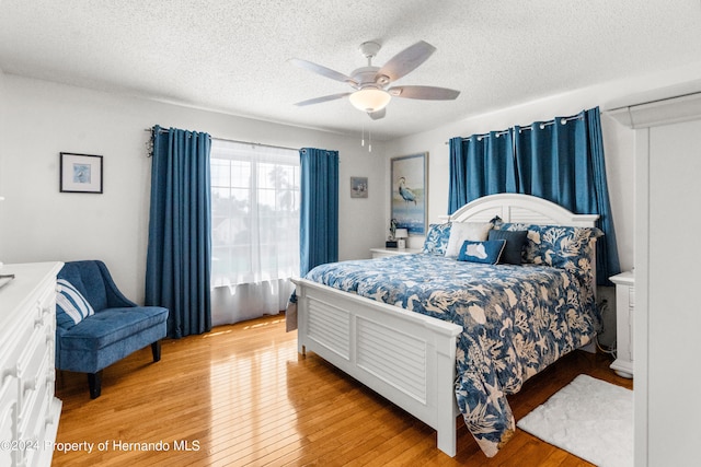 bedroom featuring ceiling fan, a textured ceiling, and light wood-type flooring