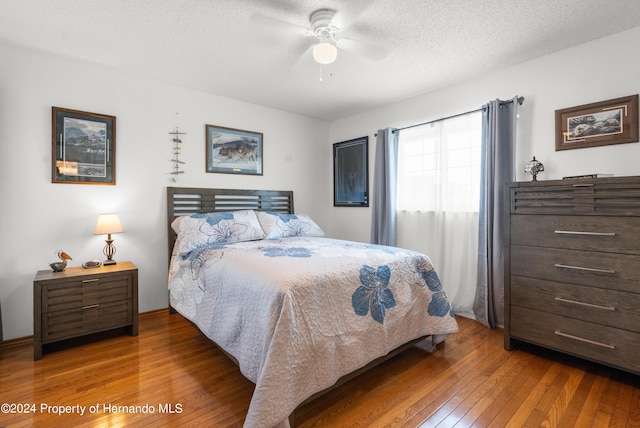 bedroom featuring ceiling fan, wood-type flooring, and a textured ceiling