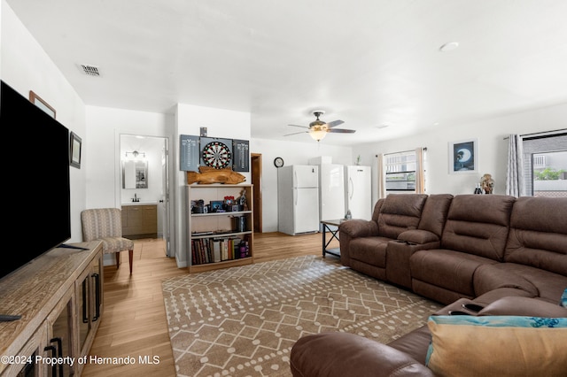 living room with light hardwood / wood-style floors, ceiling fan, and a healthy amount of sunlight