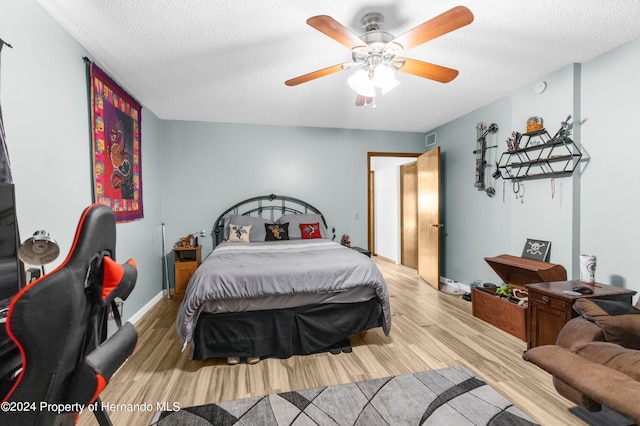 bedroom with a textured ceiling, hardwood / wood-style flooring, and ceiling fan