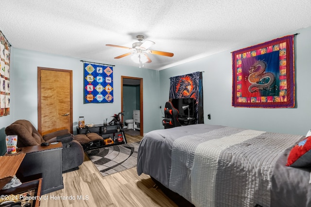 bedroom with a textured ceiling, light hardwood / wood-style flooring, and ceiling fan