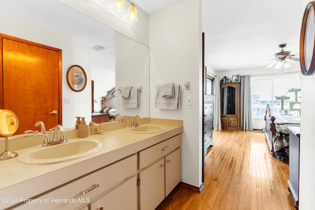 bathroom featuring a textured ceiling, vanity, hardwood / wood-style flooring, and ceiling fan