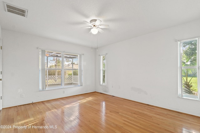 empty room featuring a wealth of natural light, hardwood / wood-style flooring, and ceiling fan