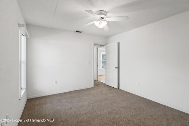 carpeted empty room featuring ceiling fan and a textured ceiling