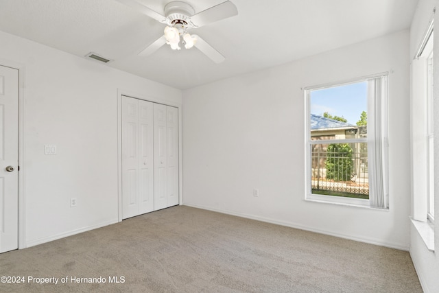 unfurnished bedroom with light colored carpet, ceiling fan, and a closet