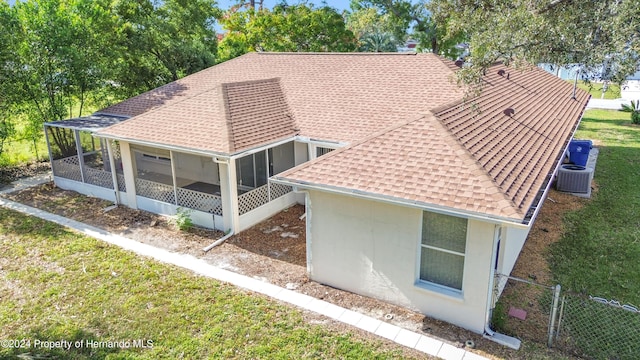 rear view of property featuring a sunroom, a yard, and central AC