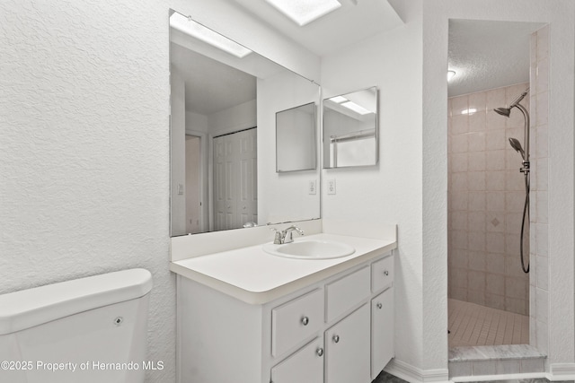 bathroom featuring vanity, a tile shower, a textured ceiling, and toilet