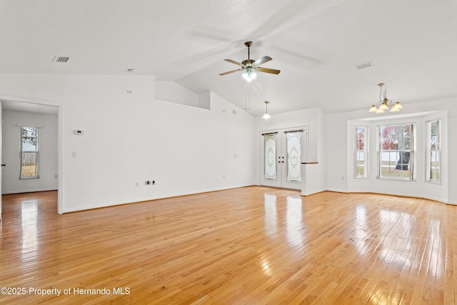 unfurnished living room with lofted ceiling, ceiling fan with notable chandelier, and light hardwood / wood-style flooring