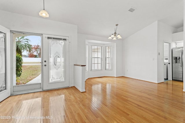 entryway with lofted ceiling, light hardwood / wood-style flooring, and a chandelier