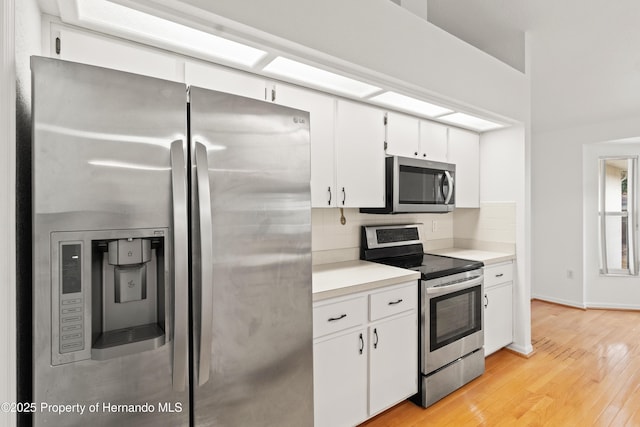 kitchen featuring white cabinetry, appliances with stainless steel finishes, backsplash, and light wood-type flooring