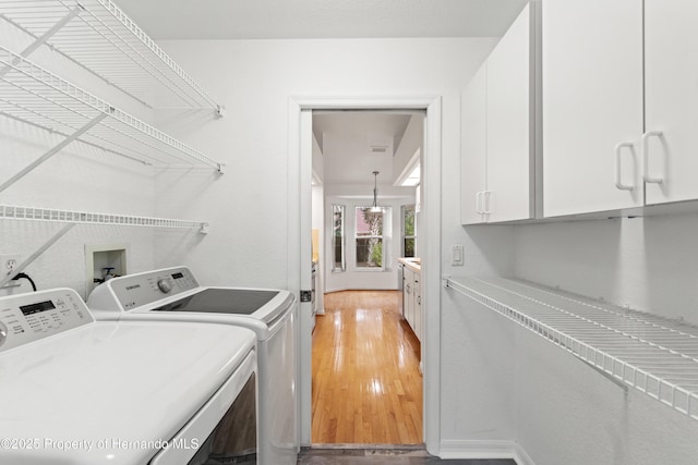 washroom featuring cabinets, washer and clothes dryer, and light hardwood / wood-style flooring