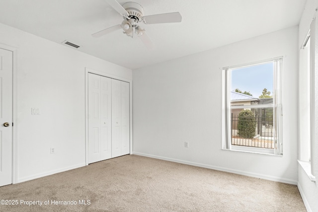 unfurnished bedroom featuring light carpet, a closet, and ceiling fan