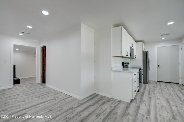 kitchen with stainless steel appliances, white cabinetry, and light hardwood / wood-style flooring