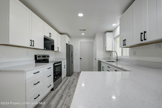 kitchen featuring light stone counters, stainless steel appliances, sink, white cabinets, and light hardwood / wood-style flooring