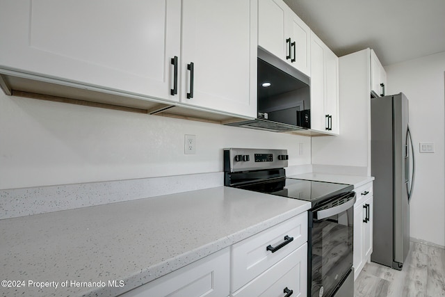 kitchen with stainless steel appliances, light hardwood / wood-style floors, white cabinetry, and light stone counters