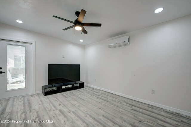 unfurnished living room featuring ceiling fan, light hardwood / wood-style floors, and a wall mounted AC