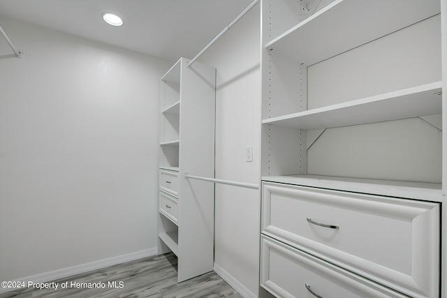 walk in closet with light hardwood / wood-style flooring