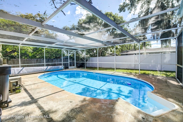 view of swimming pool with glass enclosure and a patio area