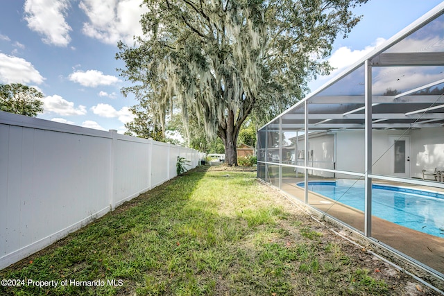 view of yard with glass enclosure and a fenced in pool