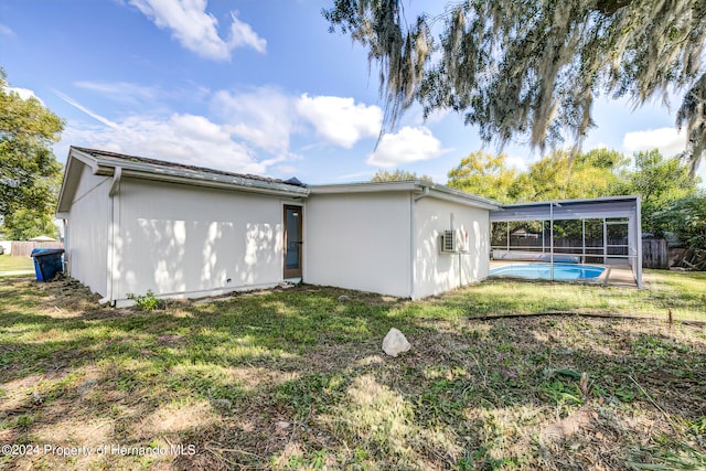 back of property with a fenced in pool and a yard