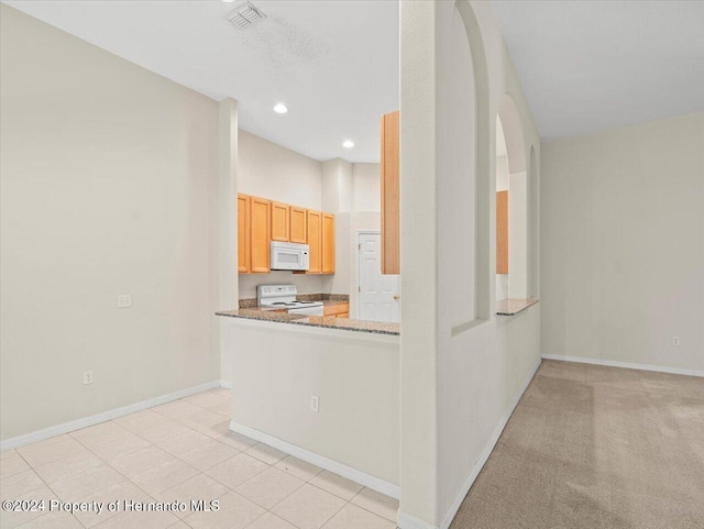 4264 Braemere Dr, Brooksville, FL 34609 - kitchen with light stone counters, kitchen peninsula, light carpet, light brown cabinetry, and white appliances