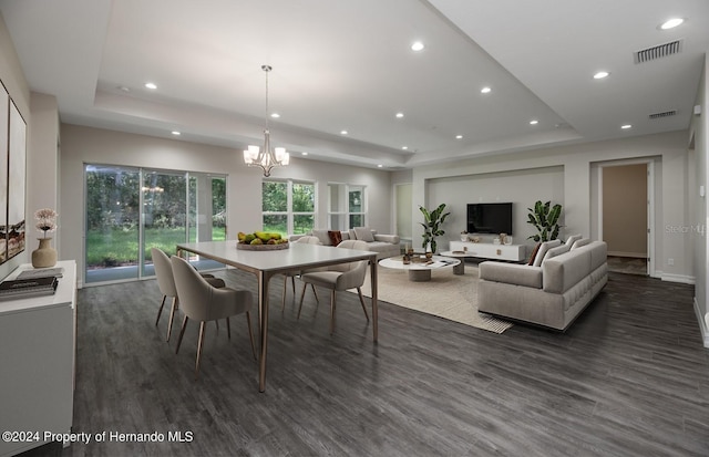 dining space featuring dark hardwood / wood-style floors, a raised ceiling, and an inviting chandelier