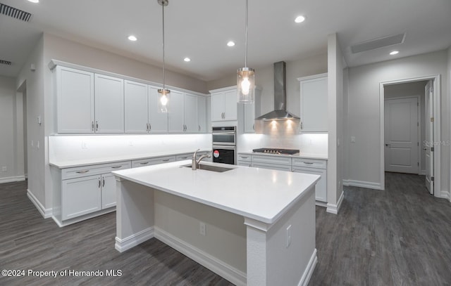 kitchen featuring a center island with sink, wall chimney exhaust hood, white cabinetry, and sink