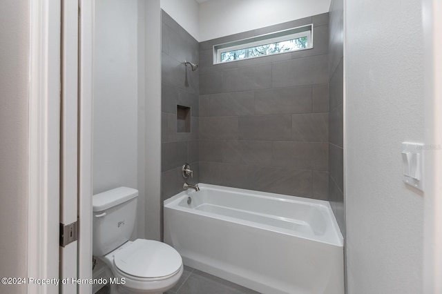 bathroom featuring tile patterned flooring, tiled shower / bath combo, and toilet