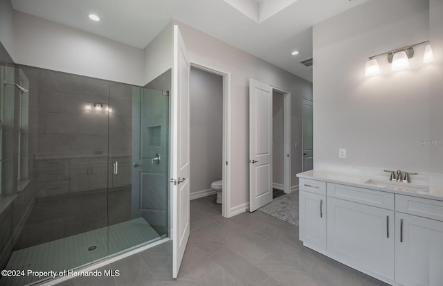 bathroom with toilet, vanity, tile patterned flooring, and a shower with shower door