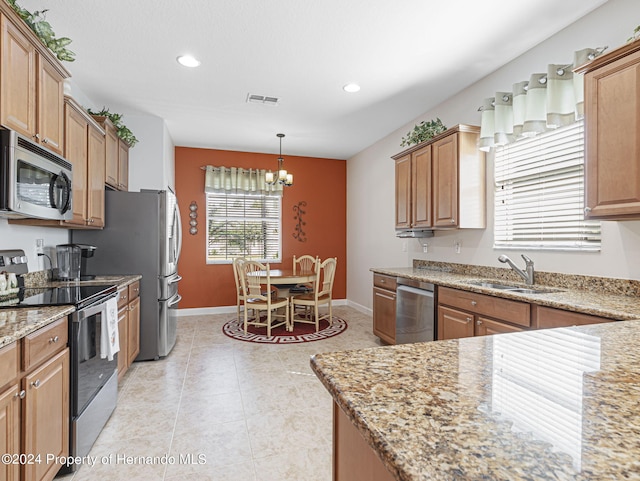 kitchen with decorative light fixtures, appliances with stainless steel finishes, sink, and light stone counters