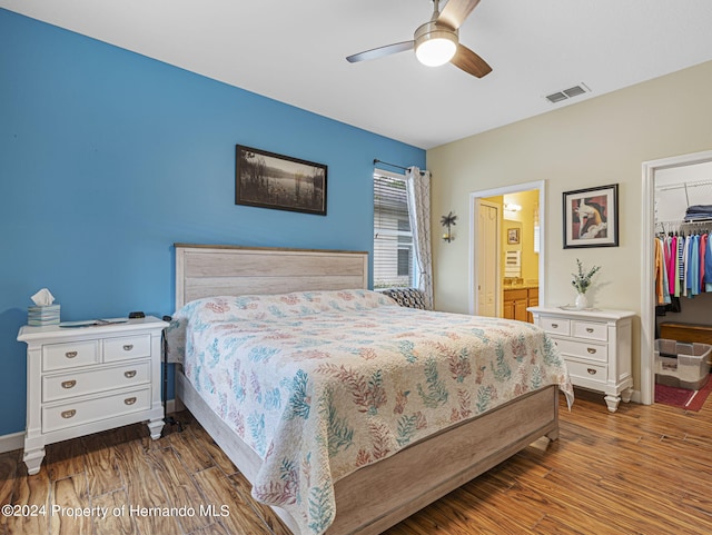 bedroom with a spacious closet, ceiling fan, a closet, and dark hardwood / wood-style flooring