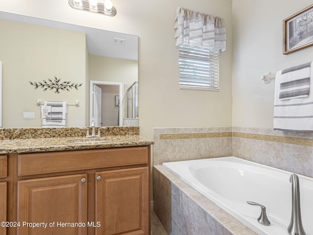 bathroom with vanity and a relaxing tiled tub