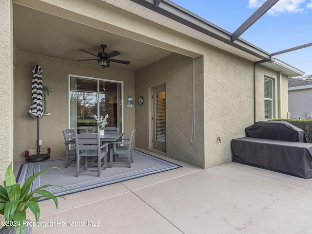 view of patio / terrace featuring glass enclosure, area for grilling, and ceiling fan