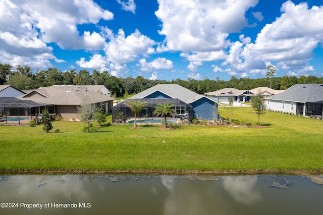 back of property featuring a water view, glass enclosure, and a lawn