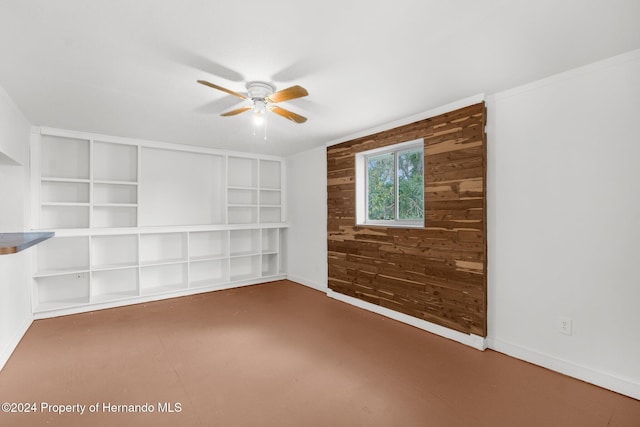 empty room featuring ceiling fan and built in shelves