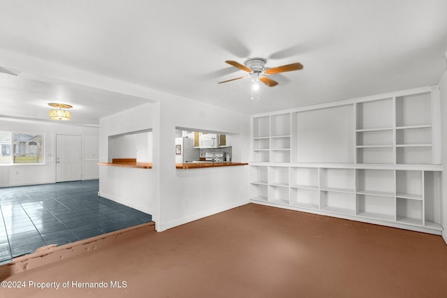 spare room featuring built in features, ceiling fan, and dark tile patterned floors