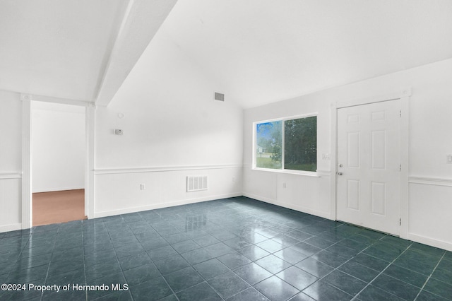 tiled spare room featuring lofted ceiling