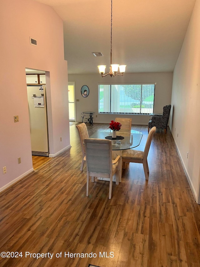 dining area featuring lofted ceiling, a chandelier, and dark hardwood / wood-style flooring