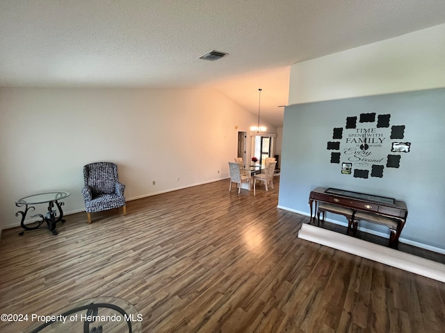 living area featuring dark hardwood / wood-style flooring, lofted ceiling, a textured ceiling, and a notable chandelier